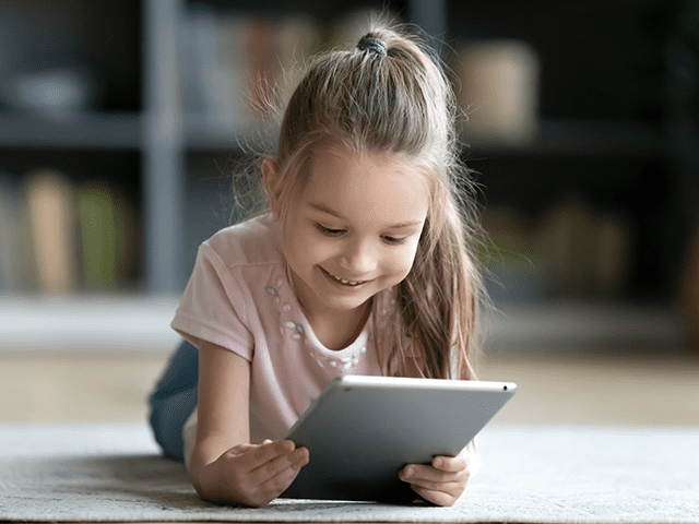 Μικρό κορίτσι με tablet που μπαίνει στο Ιντερνετ για ψυχαγωγία.