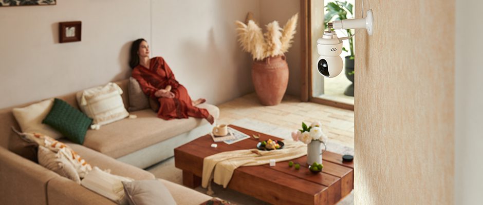 Aqara Camera E1 σε επιτοίχια τοποθέτηση σε σαλόνι, όπου κάθεται γυναίκα σε καναπέ. Η κάμερα είναι γυρισμένη σε γωνία που δεν καταγράφει τη γυναίκα.