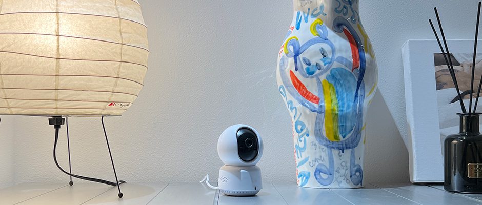 Η Aqara Camera E1 τοποθετημένη και σε λειτουργία σε επιφάνεια τραπεζιού σπιτιού, δίπλα σε άλλα αντικείμενα.